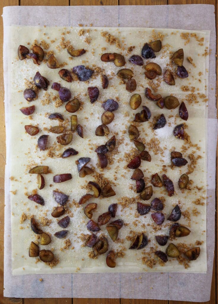 Adding sugar on top of the plums.